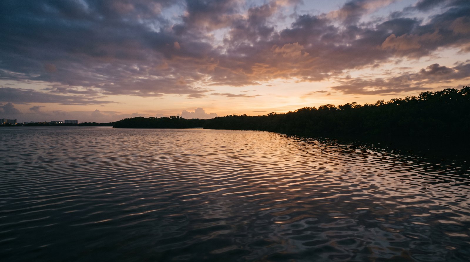 Atardecer en tonos ámbar y violeta reflejado sobre la superficie en calma de la Laguna Nichupté en Cancún