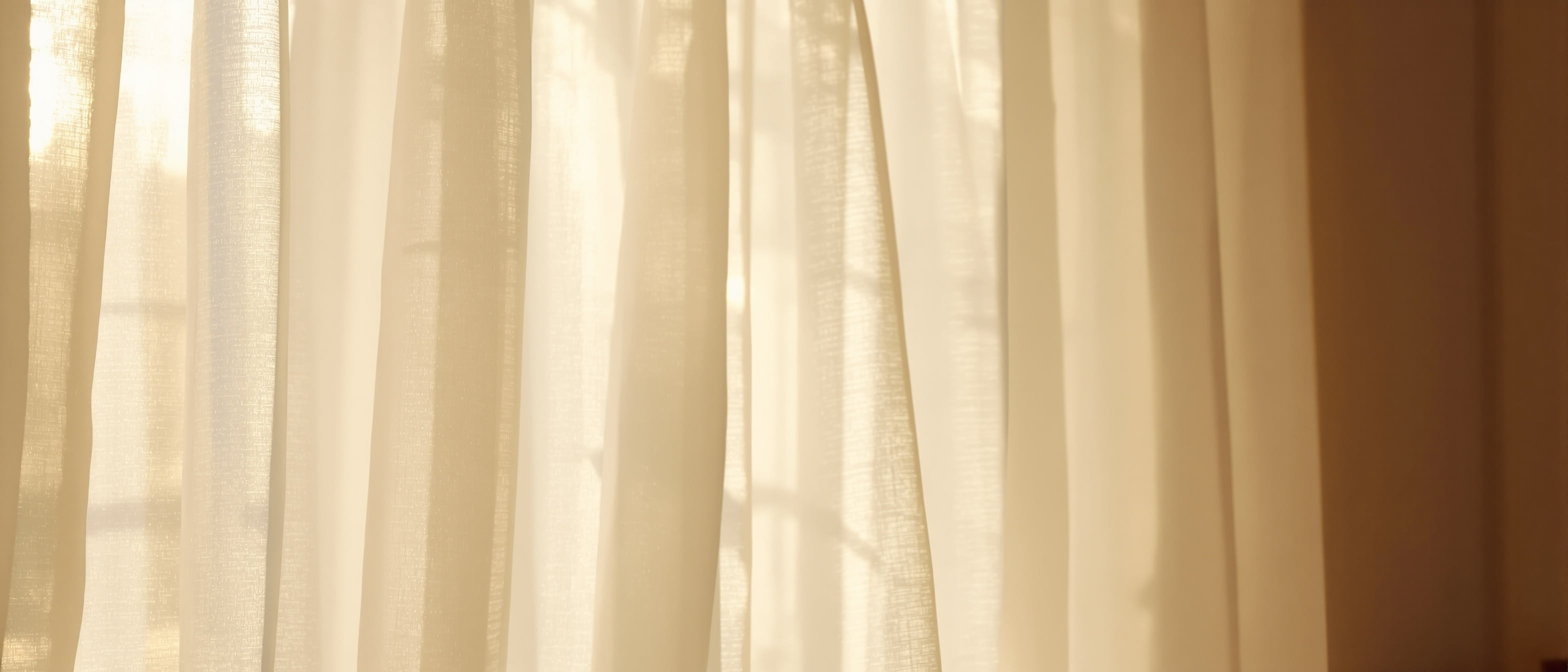 Cortina de lino blanco ondeando suavemente con luz dorada